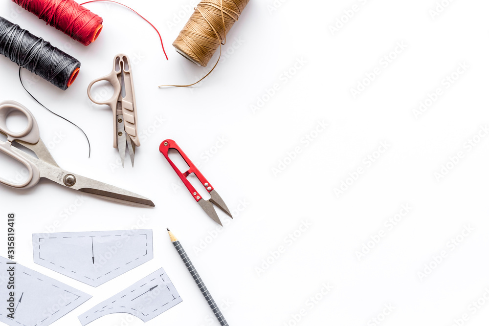Clothes designer work desk. Pattern, scissors, thread on white background top-down copy space Clothes designer work desk. Pattern, scissors, thread on white background top-down copy space