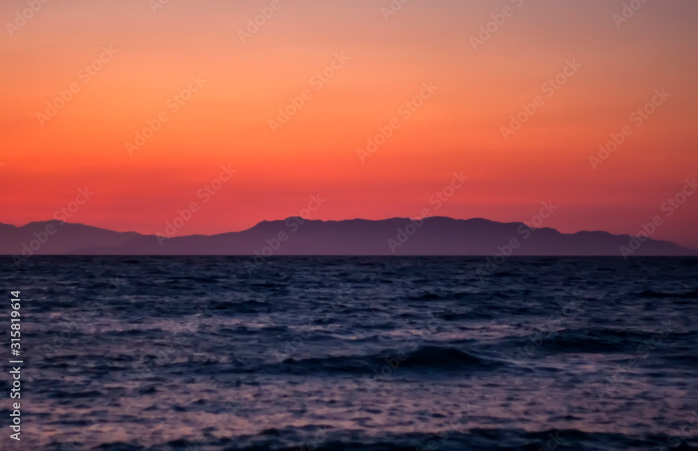 Obraz premium mountains and sea on a background of red sunset