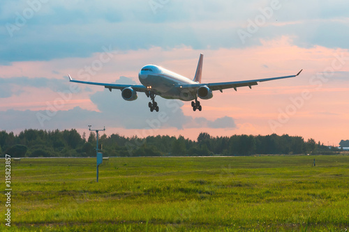 Passenger airplane landing on runway at airport, early evening.
