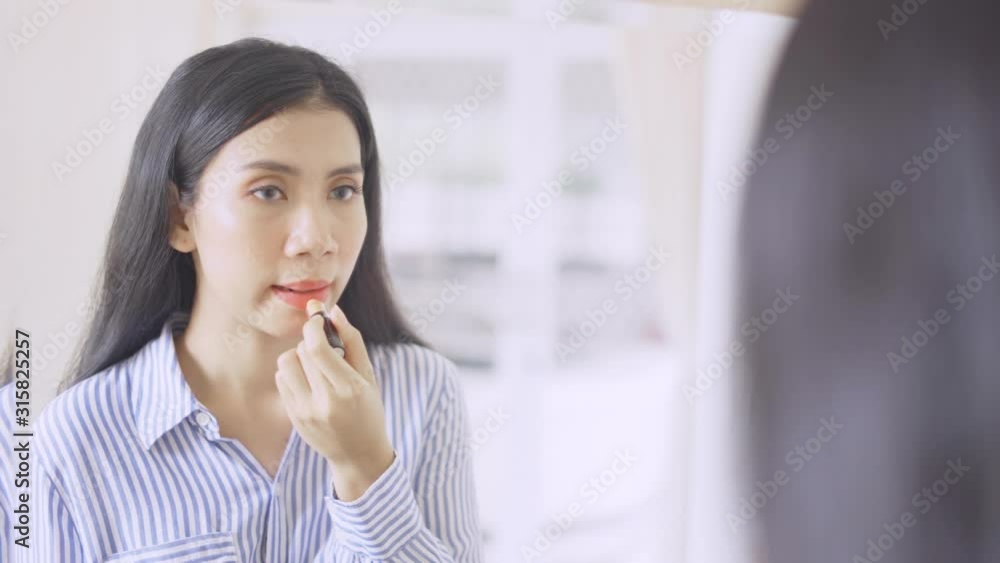 Pretty businesswoman getting ready to work while applying lipstick in front of the mirror at home. Shot in 4k resolution Pretty businesswoman getting ready to work while applying lipstick in front of the mirror at home. Shot in 4k resolution