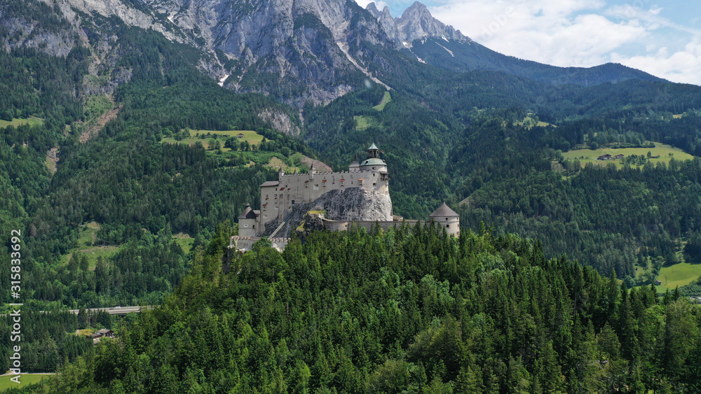 Aerial panoramic view of Hohenwerfen Castle, Austria. Medieval rock fortress in Alpine mountains with spruces. Overlooking the Werfen town in Salzach valley. Summer.