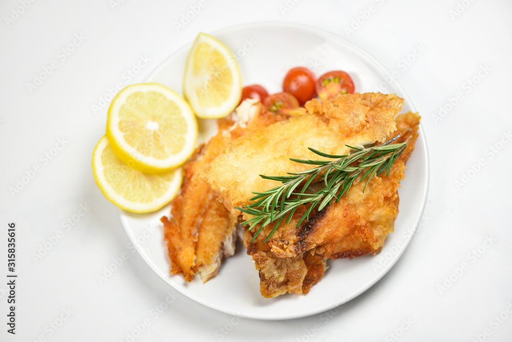 fried fish fillet sliced for steak or salad cooking food with herbs spices rosemary and lemon tilapia fillet fish crispy served on white plate fried fish fillet sliced for steak or salad cooking food with herbs spices rosemary and lemon tilapia fillet fish crispy served on white plate