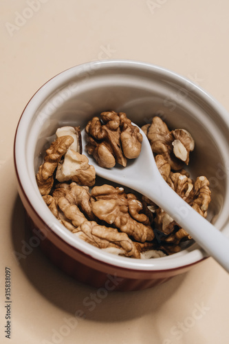 Pile of shelled walnuts in glass bowl, healthy eating concept 