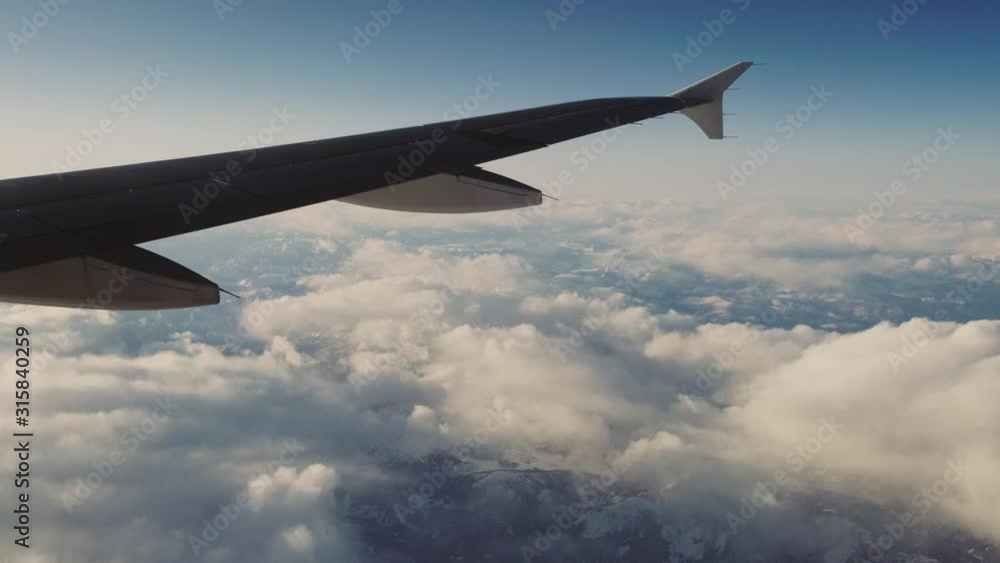 Airplane wing flying over fluffy clouds Airplane wing flying over fluffy clouds