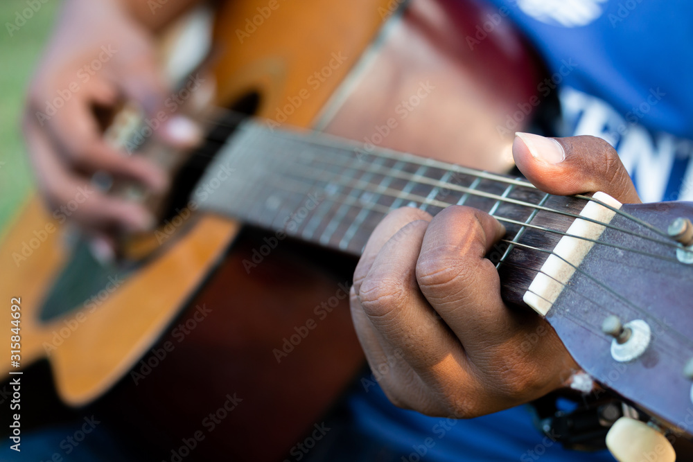 Man's hands playing acoustic guitar, soft focus.
