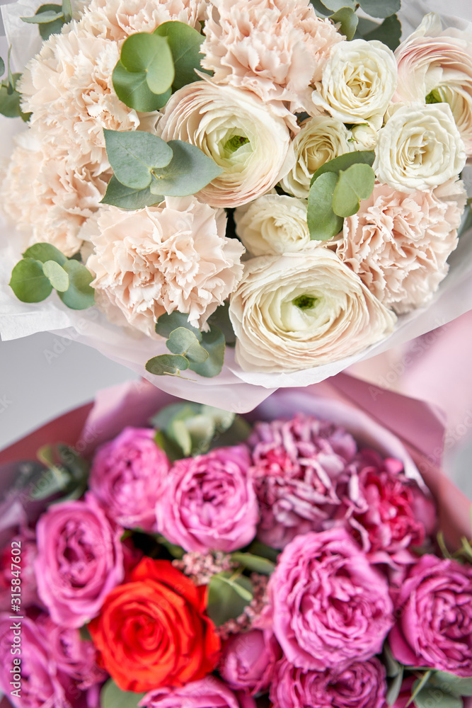 Obraz premium Two Beautiful bouquets of mixed flowers in womans hands. the work of the florist at a flower shop. Delivery fresh cut flower. European floral shop.