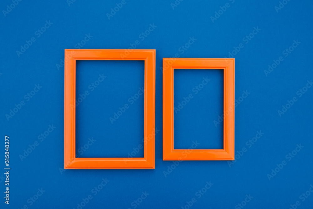 Empty orange frame on the classic blue background. Trendy greeting card. Minimal concept. Copy space for your text. Flat lay style. Top view. Empty orange frame on the classic blue background. Trendy greeting card. Minimal concept. Copy space for your text. Flat lay style. Top view.