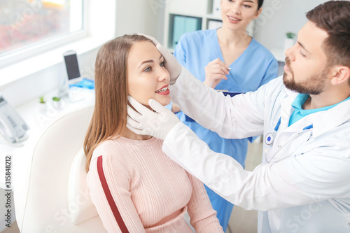 Fotografie Plastic surgeon examining young woman's face prior to operation in clinic