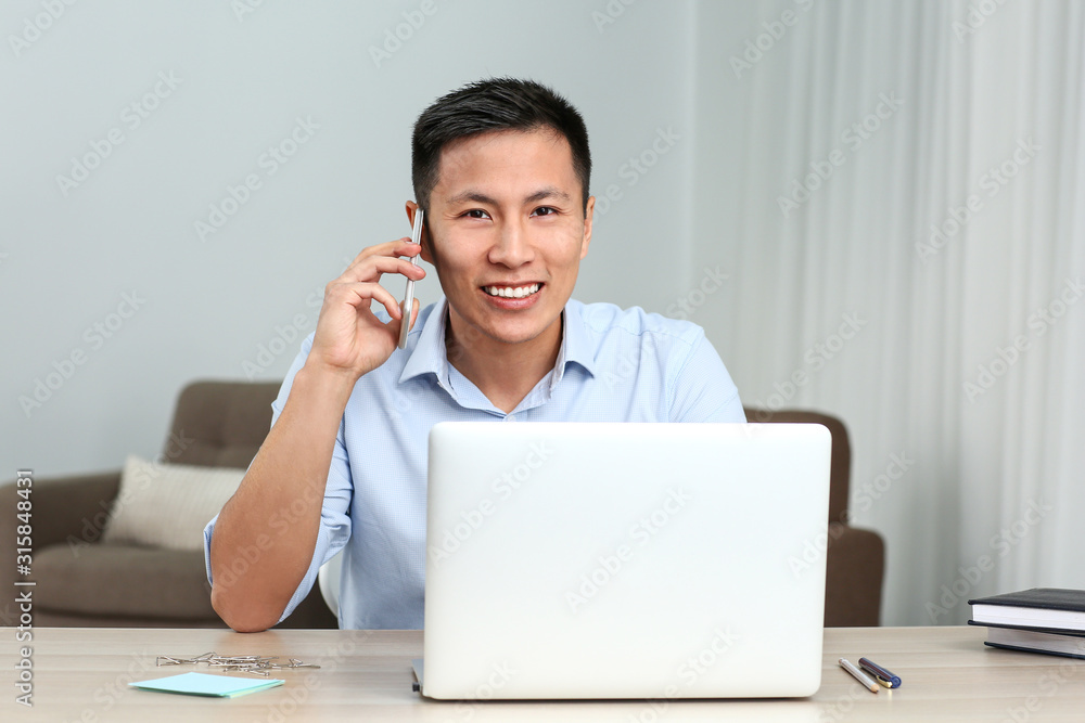 Portrait of Asian businessman talking by phone while working in office Portrait of Asian businessman talking by phone while working in office