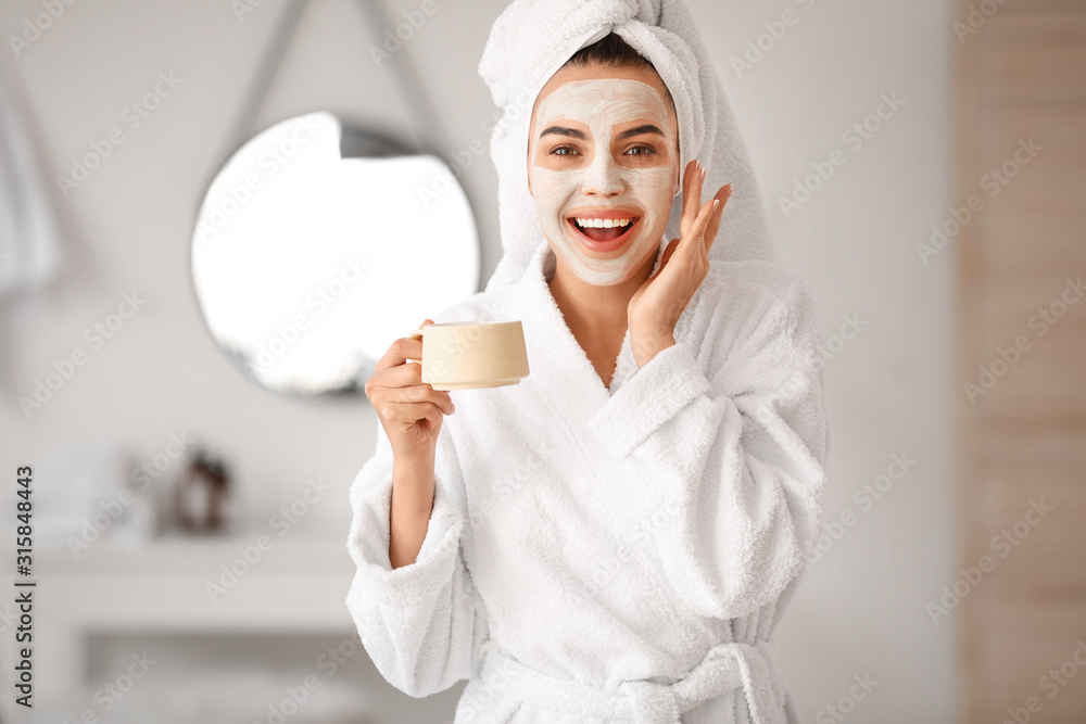 Beautiful young woman with facial mask drinking coffee in bathroom Beautiful young woman with facial mask drinking coffee in bathroom