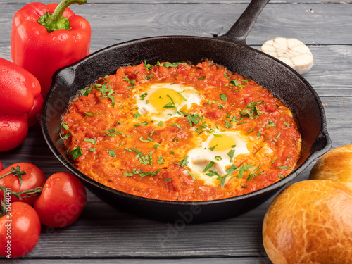 Shakshuka with bell pepper, tomatoes, hummus and rolls.