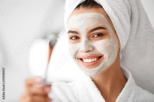 Quadro su tela Beautiful young woman applying facial mask in bathroom