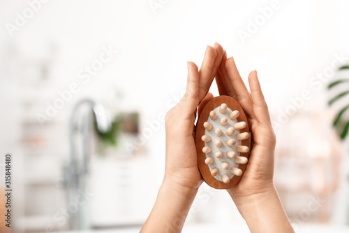 Hands of young woman with massage brush in bathroom