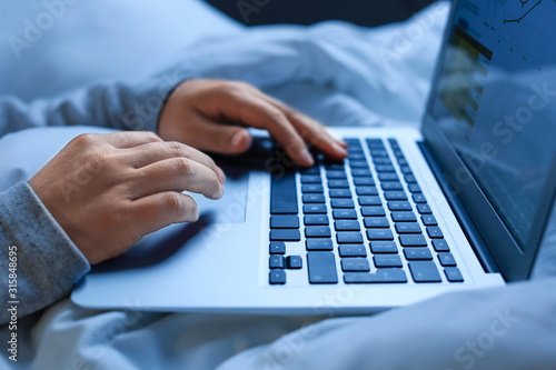 Person using laptop in bed ...