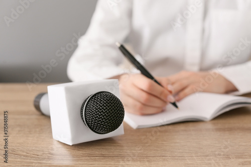 Female journalist with microphone having an interview in office, closeup