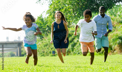 Happy children with parents running in park