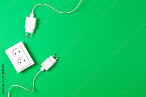 White electrical power sockets and power plug on light green background. Top view