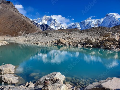 Ngozumpa Tsho, the fifth Gokyo lake., hills and snow-capped mountains. Beautiful reflection in the water. Sunny day and marvellous blue sky. Gokyo lakes and Cho Oyu base camp trek, Solokhumbu, Nepal.
