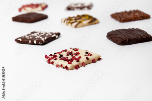 Many beautiful multi-colored cookies in chocolate on a white background