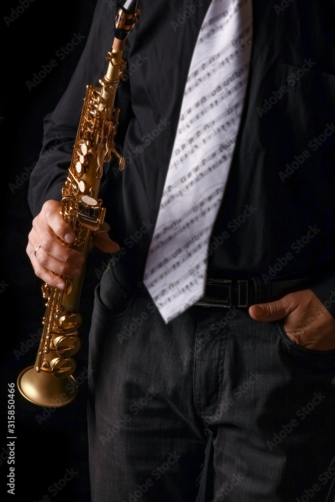 Naklejka premium soprano saxophone in the hands of a guy on a black background