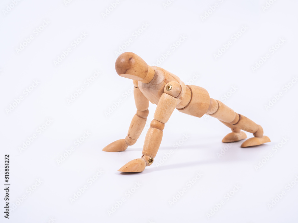 Small wooden dummy during push ups on white background Small wooden dummy during push ups on white background
