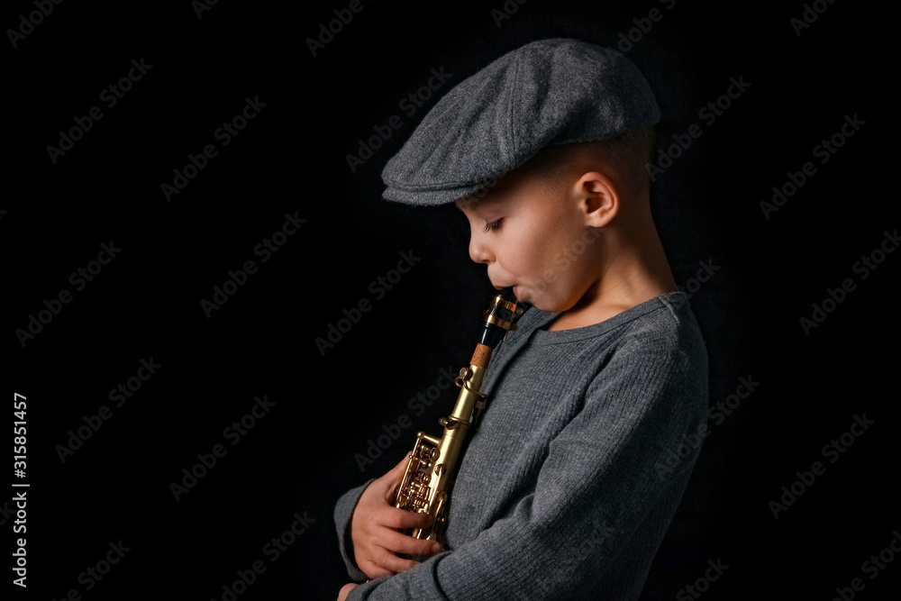 Naklejka premium happy child plays saxophone in studio