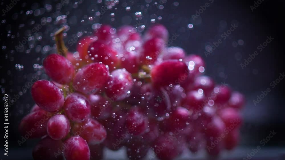 Red grapes fall into water with splashes super slow motion shot