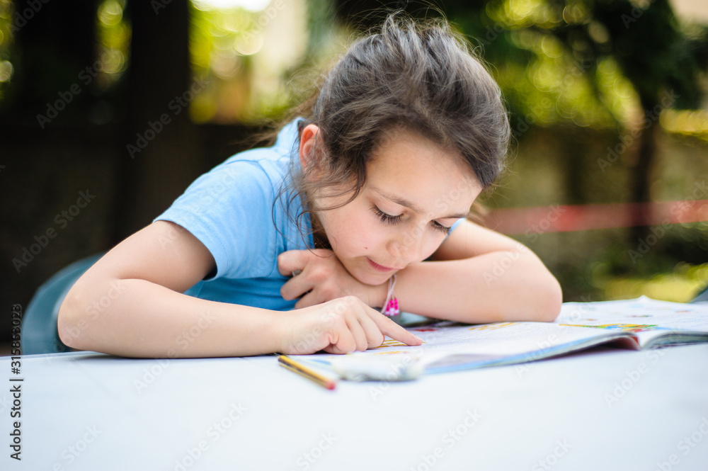 little girl reads a book on the garden table-little girl learns to read little girl reads a book on the garden table-little girl learns to read