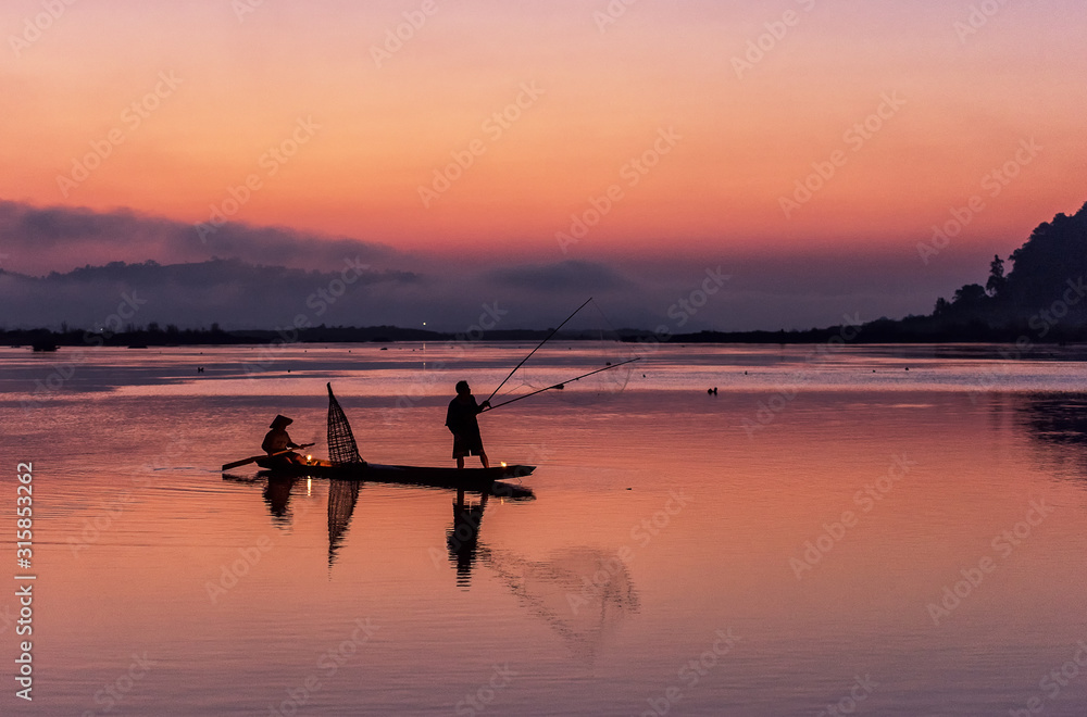 Silhouette of fisherman on wooden boat in nature lake with sunrise Silhouette of fisherman on wooden boat in nature lake with sunrise