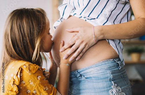 Canvastavla Happy kid girl hugging pregnant mother's belly