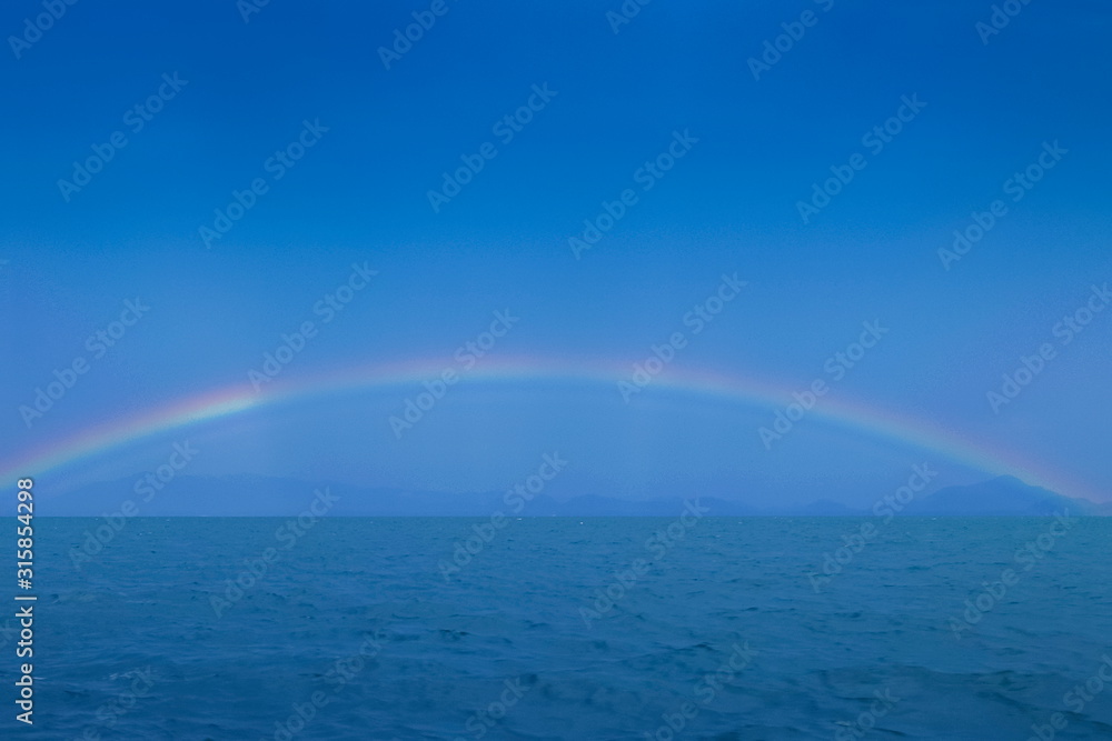 view of raining with rainbow in the sea, Trang sea, south of Thailand.