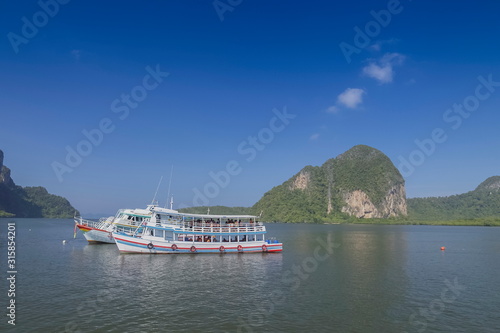 view of a white touring boat floating in the sea with blue sky background, Trang sea, southern Thailand.