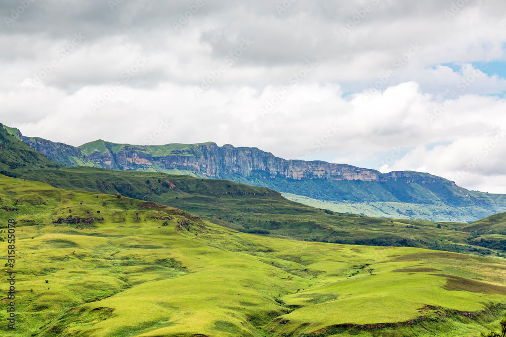 View to steep rocky mountains, with green and soft meadows in the foreground, Maloti Drakensberg Park, South Africa