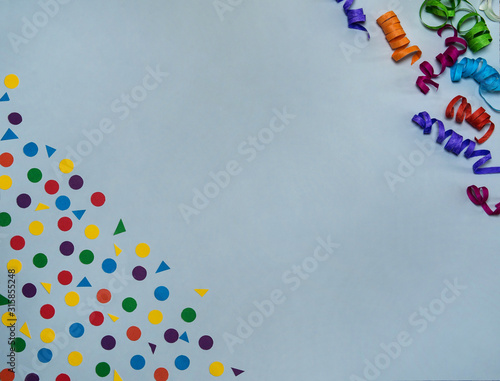 The concept of birthday. Border of colored paper streamers and confetti on a gray background. Free space.