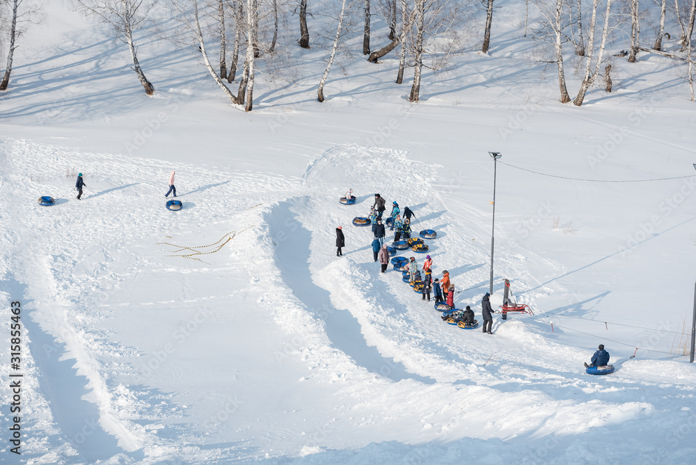 a lot of people ride a tubenge. skiing from the mountain in winter. a lot of people ride a tubenge. skiing from the mountain in winter.
