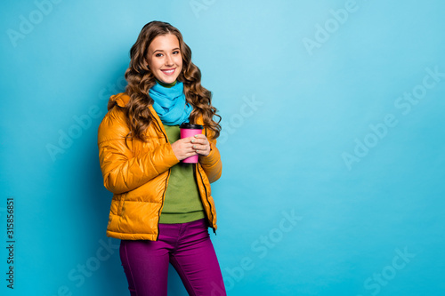 Photo of nice lady hold hot paper beverage mug enjoy autumn weather wear casual yellow overcoat scarf violet trousers green jumper isolated blue color background