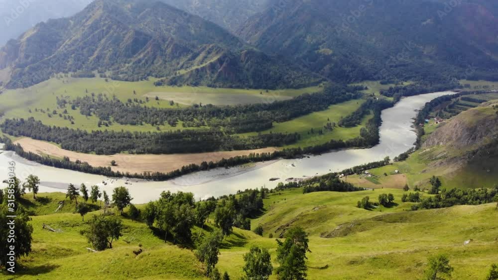 Flying over a green valley with a river and wild mountains Flying over a green valley with a river and wild mountains