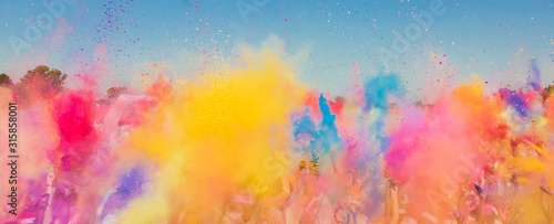 Crowd throwing bright colored powder paint in the air at Holi Festival Dahan photo