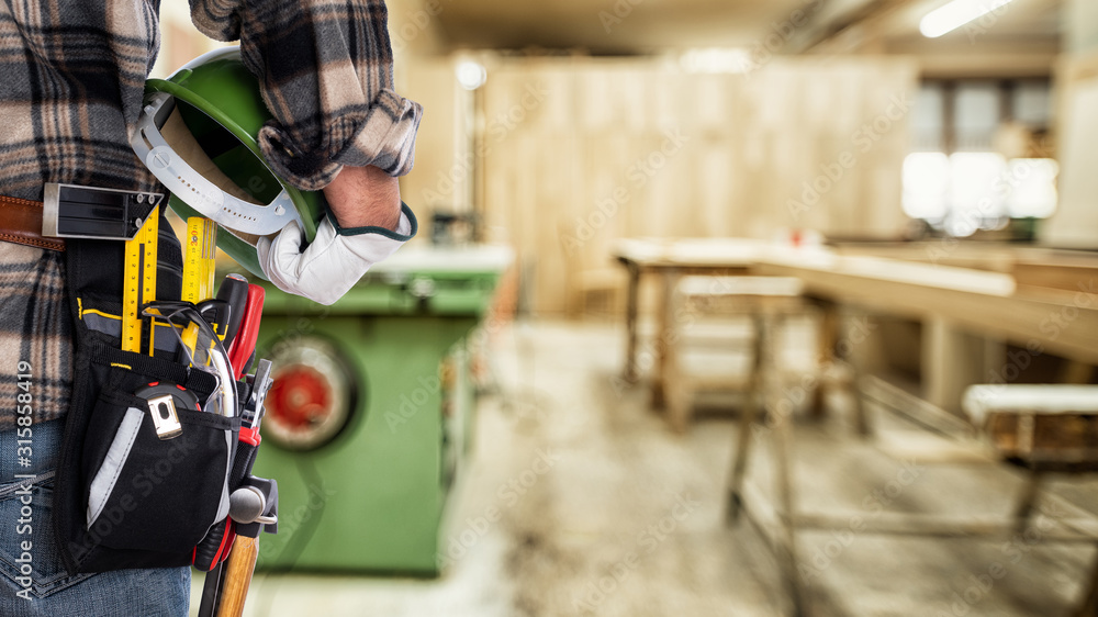 Fototapeta premium Close-up. Carpenter with his hands protected by gloves holds the helmet. Construction industry, carpentry workshop.