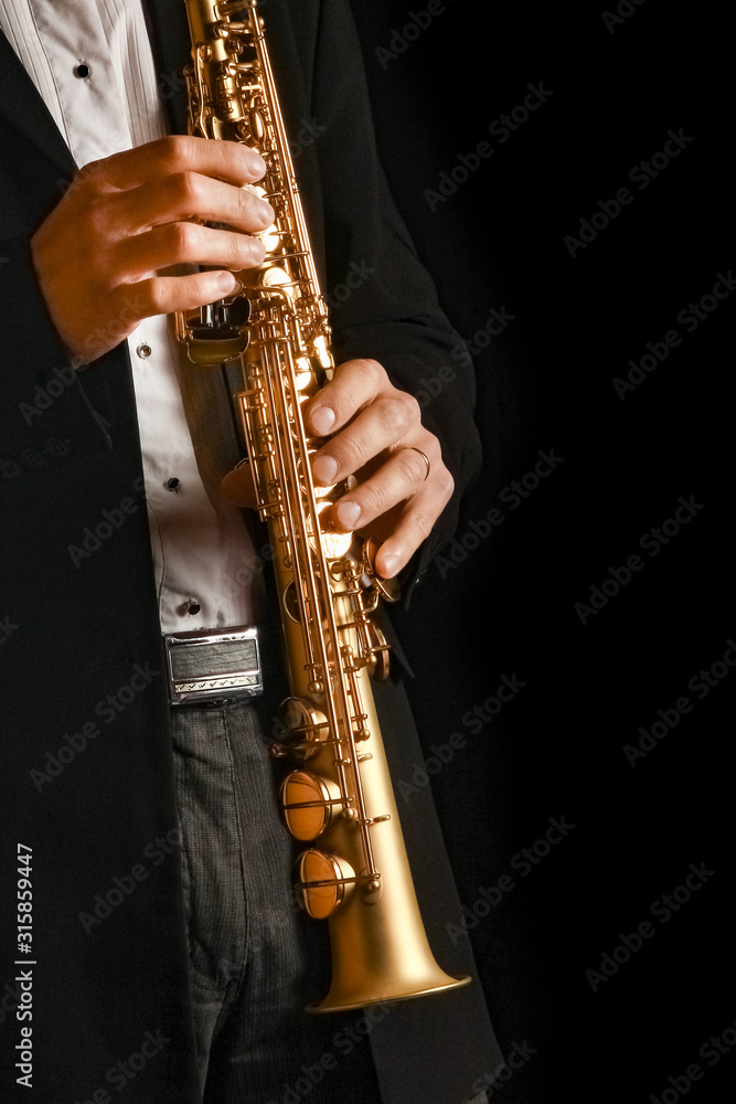 Fototapeta premium soprano saxophone in the hands of a guy on a black background