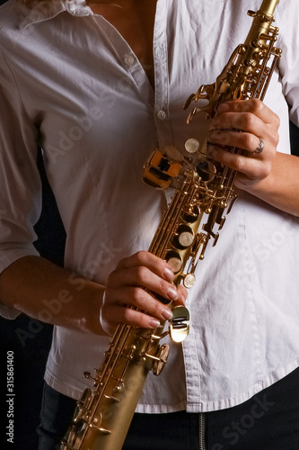 soprano saxophone in the hands of a girl on a black background photo