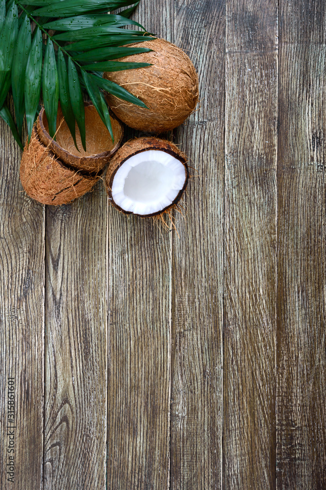 Coconut. Whole coconut, shell from coconut and green leaves on a wooden background. Big nut. Tropical fruit coconut in the shell. SPA. Food photo. Photo background. Texture tropical fruit. Copy spase.