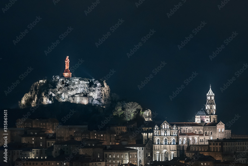 Skyline Le Puy-en-Velay in central France at twilight time; Cathedral and red christian statue