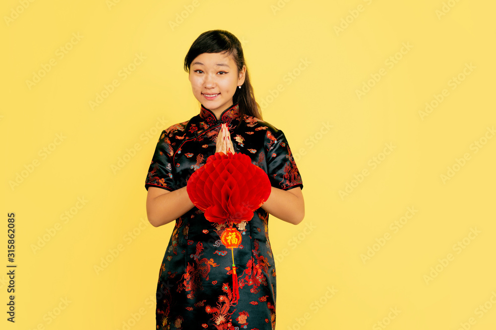 Posing with lantern, smiling, thanks. Happy Chinese New Year 2020. Asian young girl's portrait on yellow background. Female model in traditional clothes looks happy. Celebration, emotions. Copyspace. Posing with lantern, smiling, thanks. Happy Chinese New Year 2020. Asian young girl's portrait on yellow background. Female model in traditional clothes looks happy. Celebration, emotions. Copyspace.