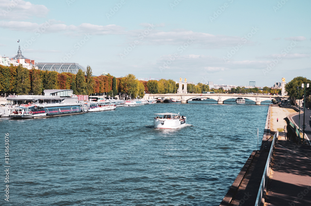 An autumn in Paris, picture of a barge cruising on the Seine river in a sunny afternoon