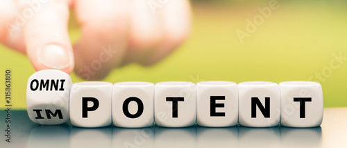 Hand turns a dice and changes the word impotent to omnipotent.