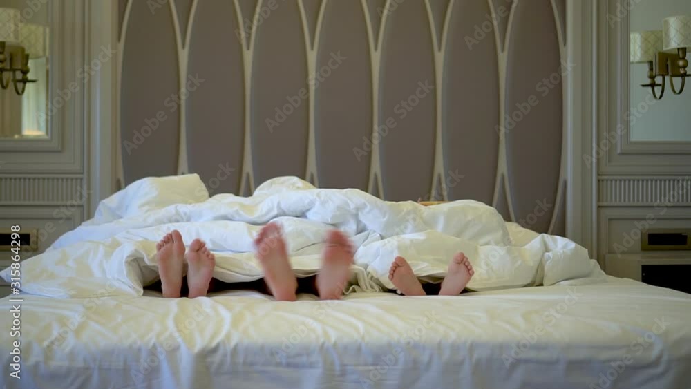 Children's legs stick out from under the blanket. Girls relax in the hotel. Travel concept with kids. Children's legs stick out from under the blanket. Girls relax in the hotel. Travel concept with kids.