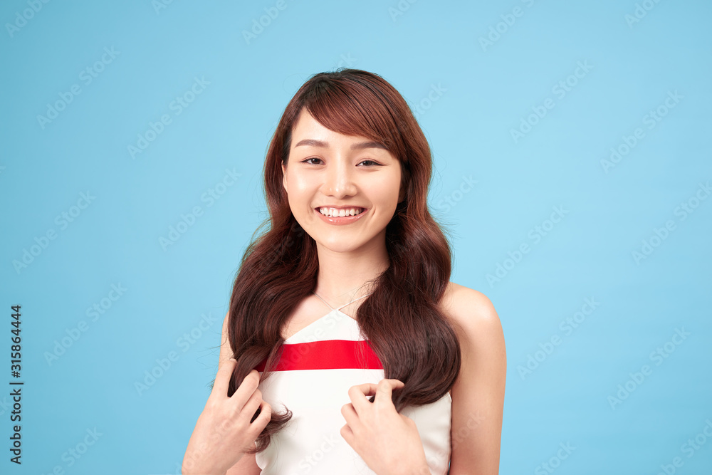 Asian woman smiling with long hair, isolated over blue background. Asian woman smiling with long hair, isolated over blue background.