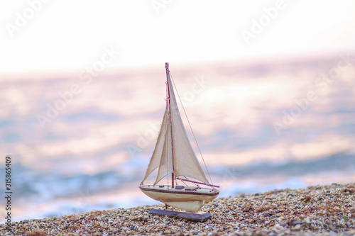 Model of a wooden ship on the background of a natural sea coast.