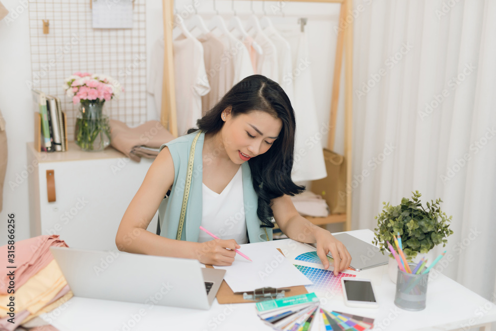 A young Asian fashion designer working on her atelier A young Asian fashion designer working on her atelier